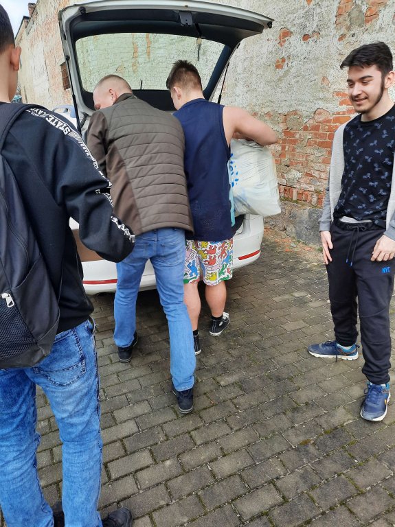 Uczniowie pakują paczki do samochodu
